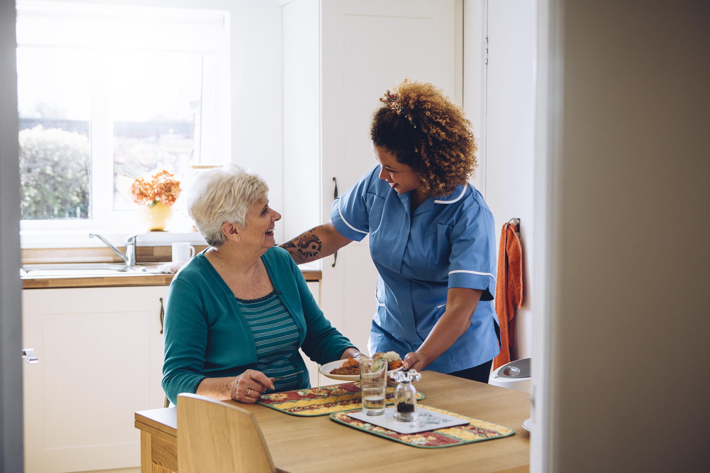 Care worker helping elderly person — NDIS support in action